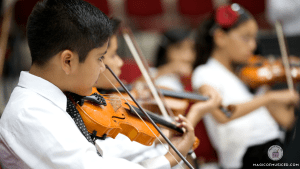 An ensemble of elementary music student actively participating in playing violins in the orchestra.
