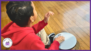 Image of an elementary music kinesthetic learner practicing rhythm and timing skills on a classroom drum.