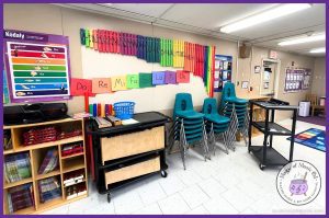 A colorful elementary music classroom with Boomwhackers mounted on the wall using spice grippers. The Kodály hand sign chart, solfege labels, and various classroom instruments are neatly organized.