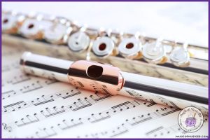 Close-up of a silver and rose gold flute resting on sheet music, used to teach the flute's role in the orchestra seating arrangement; includes Magic of Music Ed logo with a purple border.