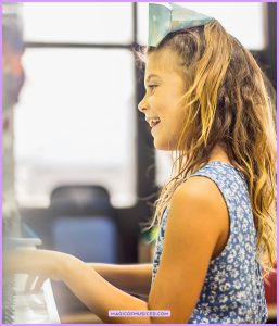 Elementary student playing piano in a classroom, highlighting music education and music education benefits like creativity and focus.