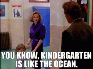 Scene from the movie Kindergarten Cop with the quote “You know, kindergarten is like the ocean,” showing a teacher talking to another adult in a school hallway.