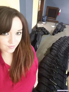 Teacher standing in front of dozens of black violin cases lined up on the floor, preparing instruments for elementary band students.