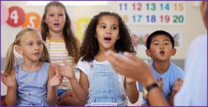 Elementary students clapping and singing together during music class, illustrating group music performance assessment skills like steady beat and pitch matching.